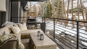 Ein Balkon mit einer Couch, Stühlen, einem kleinen Tisch und zwei Laternen.