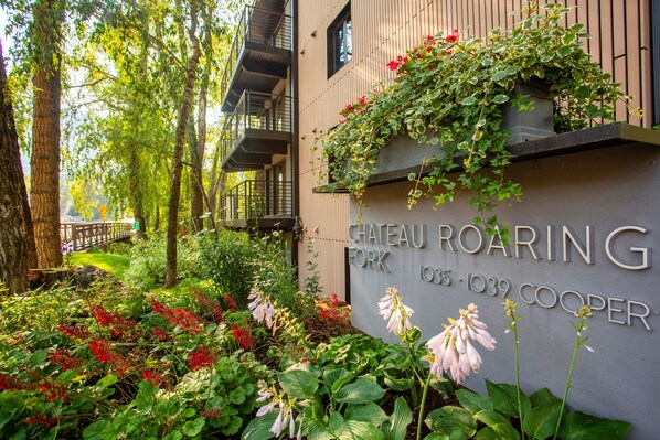 Chateau Roaring con un jardín, una valla de madera y un letrero con la dirección 105-109 Cooper.
