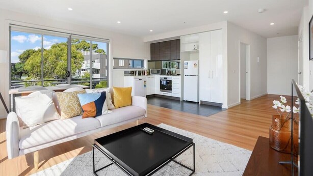 Un apartamento moderno con sala de estar, cocina y comedor. Cuenta con un ventanal que ofrece vistas al exterior.