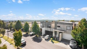 Un edificio residencial moderno con techo plano, varios portones de garaje y un área de estacionamiento.