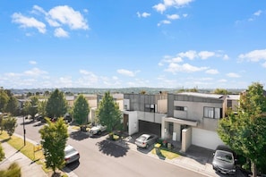 A modern residential building with a flat roof, multiple garage doors, and a parking area.