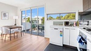 Una cocina moderna con lavavajillas, horno y ventana con vistas a un balcón.