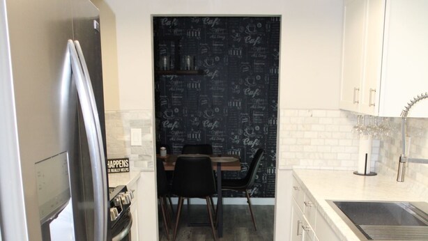 Una cocina moderna con un refrigerador de acero inoxidable, un lavavajillas y un protector contra salpicaduras negro con escritura a tiza.