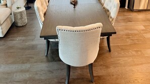 A dining area with a long table, cushioned chairs, hanging plants, and a modern light fixture. - Spacious 2 BR Urban Oasis at Castleberry Station in downtown Atlanta (Atlanta)