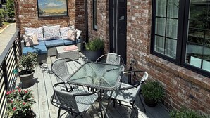 A patio with wicker furniture, a glass table, and potted plants. - Spacious 2 BR Urban Oasis at Castleberry Station in downtown Atlanta (Atlanta)