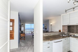 A modern kitchen with white cabinetry, a built-in oven, and a large window overlooking a balcony.