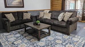 Ein Wohnzimmer mit zwei dunkelbraunen Sofas, einem Holztisch und einem gemusterten Teppich.