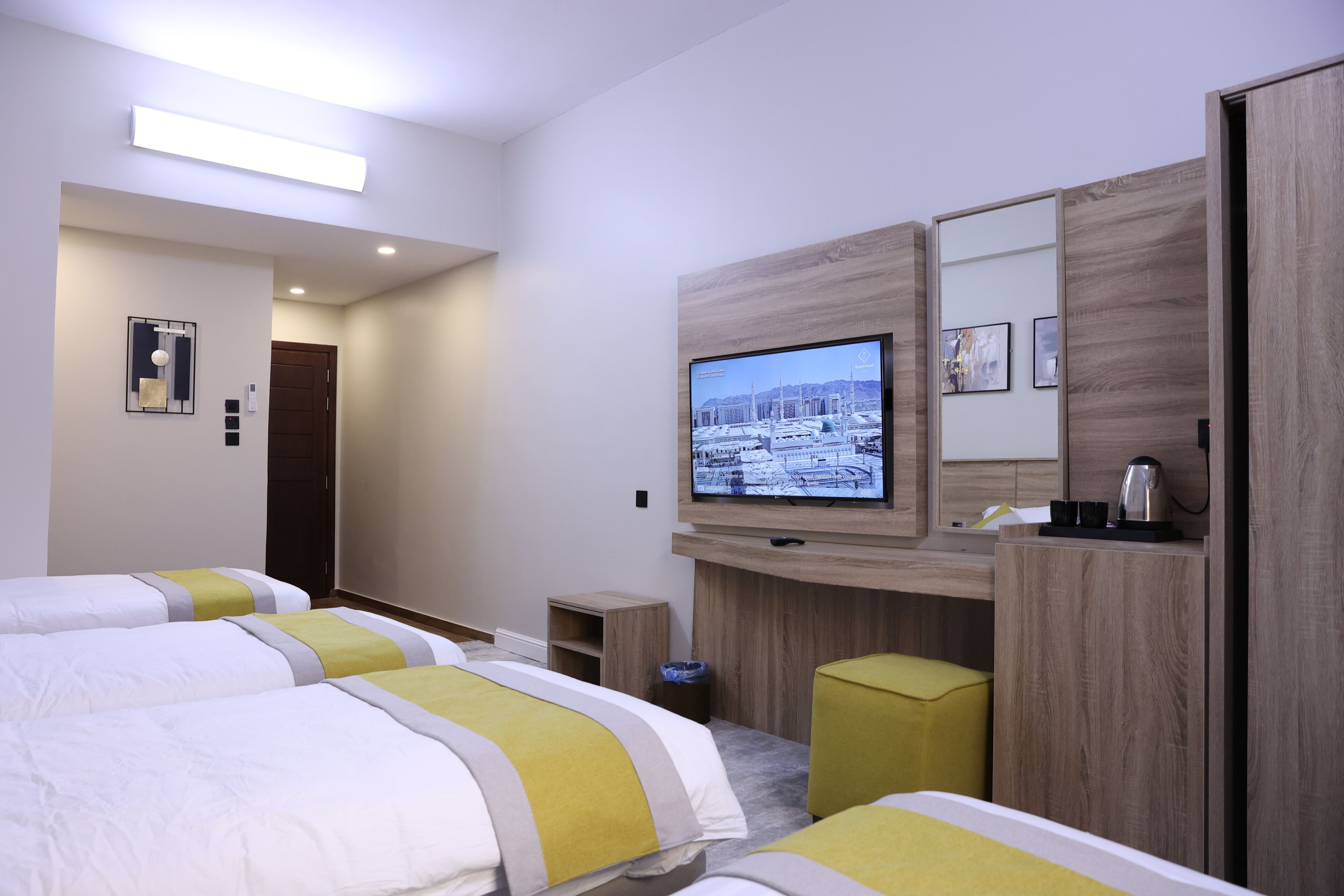 A hotel room with two beds, a television, a small table, and a wooden cabinet.