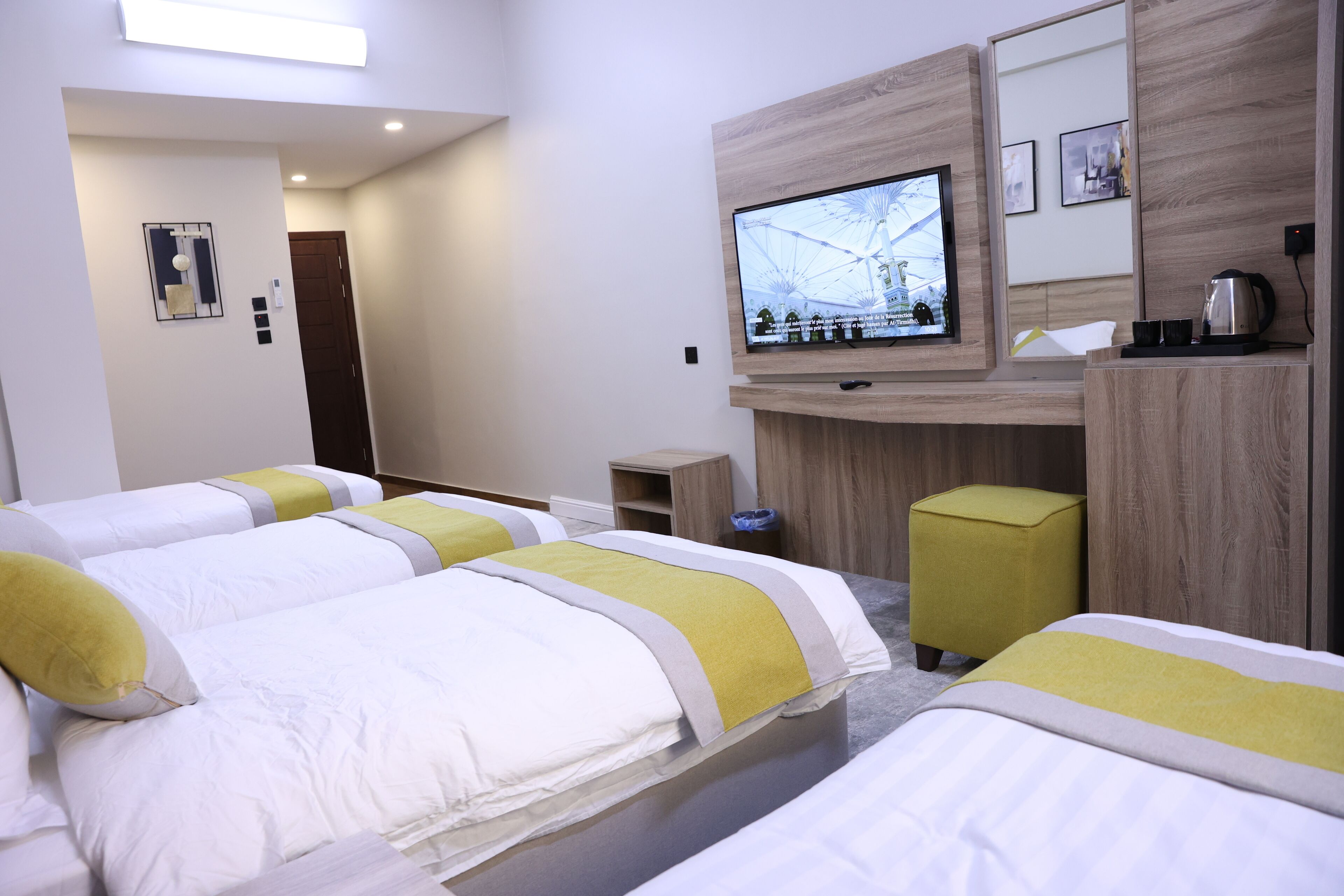 Une chambre d’hôtel avec deux lits, une télévision, une petite table et une armoire en bois.