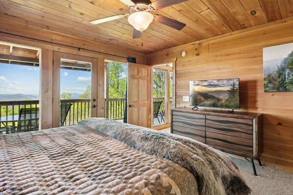 A wooden cabin bedroom with a bed, a dresser, and a television.