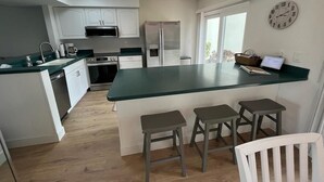 Una cocina moderna con gabinetes blancos, encimera verde y una isla integrada con taburetes.