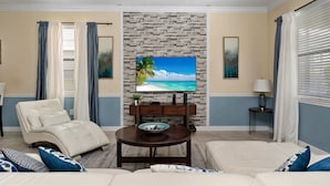 Ein Wohnzimmer mit Steinwand, Flachbildfernseher, Sofa, Couchtisch und Deckenventilator.