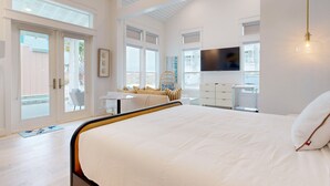 A modern bedroom with a large bed, a desk, and a TV. - Resort Pools, Golf Cart Boardwalk to Beach, Pet Friendly (Port Aransas)