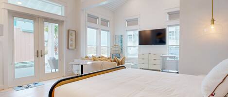 A modern bedroom with a large bed, a desk, and a TV.