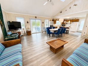 A spacious living room with a flat-screen TV, a coffee table, and striped sofas.