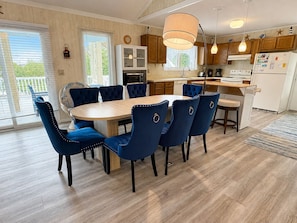 A modern kitchen with a central island, wooden cabinets, and a dining area with blue upholstered chairs.