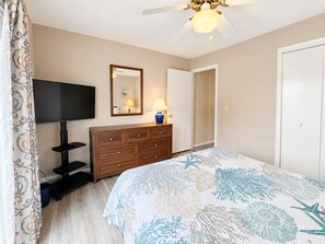 A bedroom with a bed, a dresser, a television, a mirror, and a ceiling fan. - Cuckoo's Nest - 4 Bed, 2 Bath dog friendly home with pool, hot tub and tiki bar! (Southern Shores)