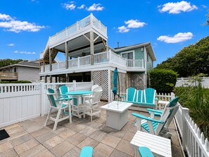A two-story building with a balcony, outdoor seating area with chairs and tables, and a white picket fence.