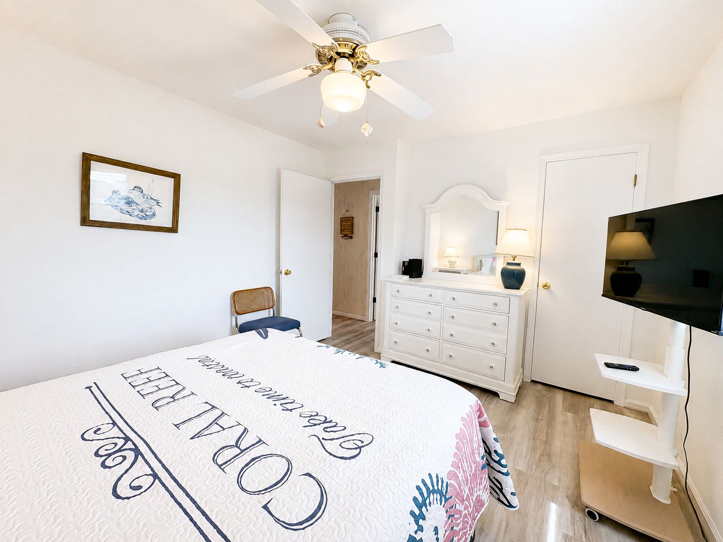 Une chambre d’hôtel équipée d’un lit, d’une commode, d’une télévision et d’un ventilateur de plafond.