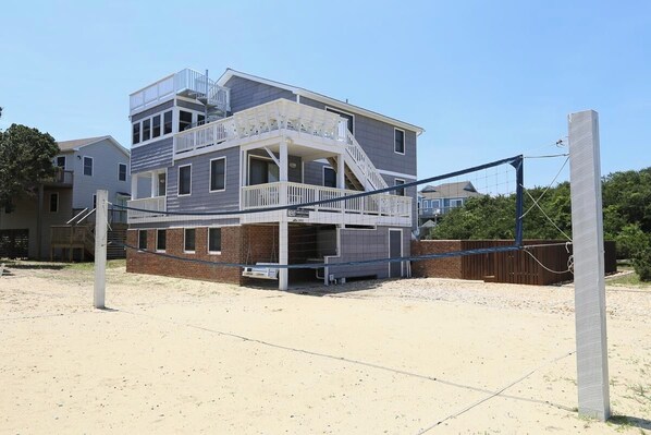 Een gebouw met twee verdiepingen, een balkon en een overdekt terras, waarschijnlijk een strandhuis.