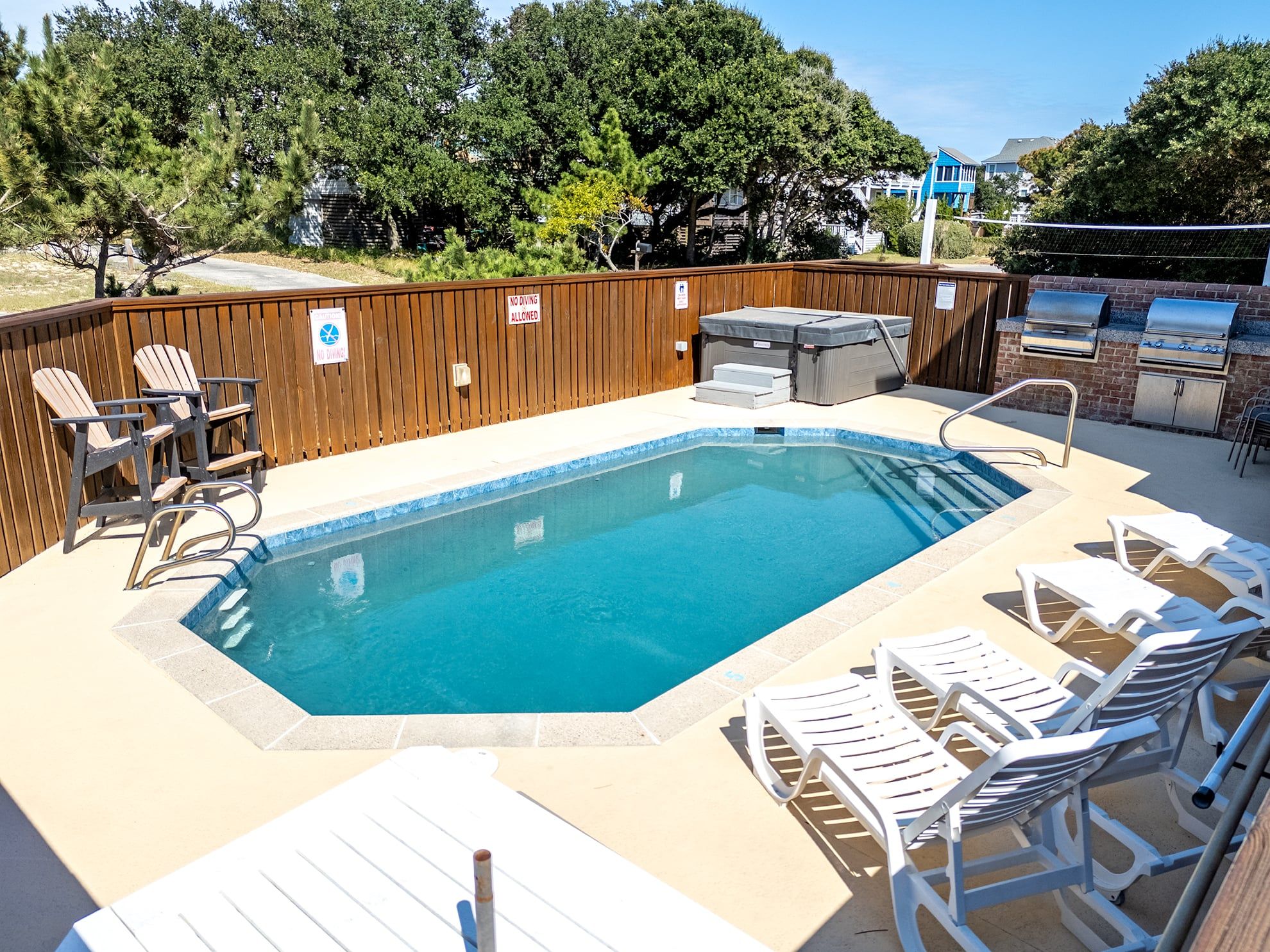 A swimming pool with lounge chairs and a barbecue area.