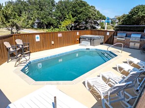 A swimming pool with lounge chairs and a barbecue area.