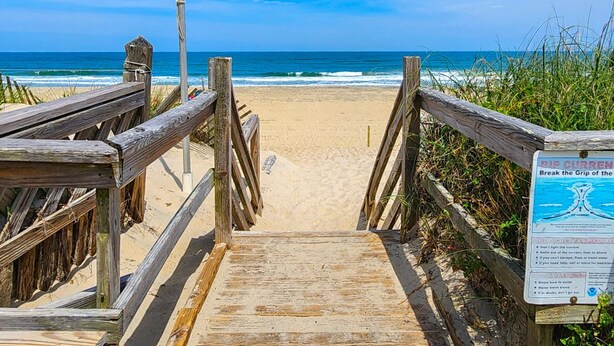 A wooden boardwalk leading to a beach with a sign warning about rip currents. - SEAS THE VIEW Oceanside, close to Duck Village, 7 bed, 4.1 bath, pool, hot tub, dogs allowed! (Duck)