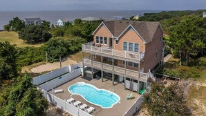 A two-story house with a large balcony and a swimming pool. - SEAS THE VIEW Oceanside, close to Duck Village, 7 bed, 4.1 bath, pool, hot tub, dogs allowed! (Duck)