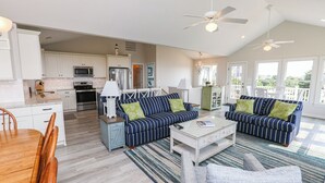 A spacious living area with a kitchen, two sofas, a coffee table, and a dining table. - SEAS THE VIEW Oceanside, close to Duck Village, 7 bed, 4.1 bath, pool, hot tub, dogs allowed! (Duck)
