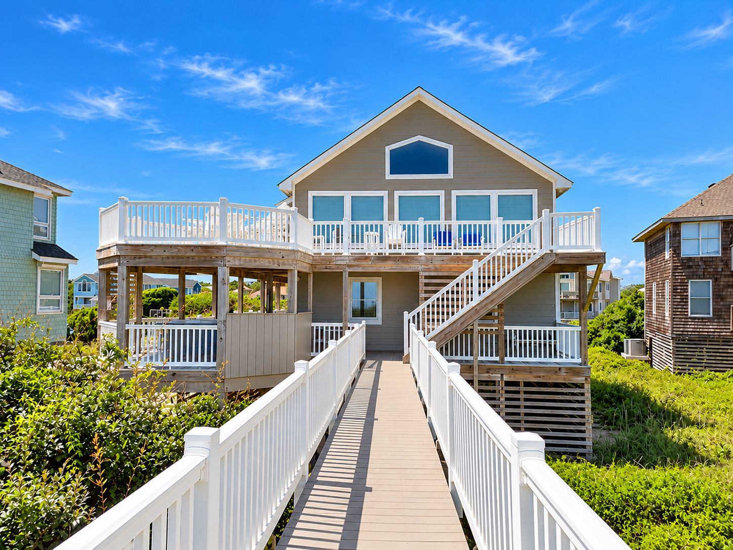 A two-story house with a covered porch and a wooden deck leading to the entrance.