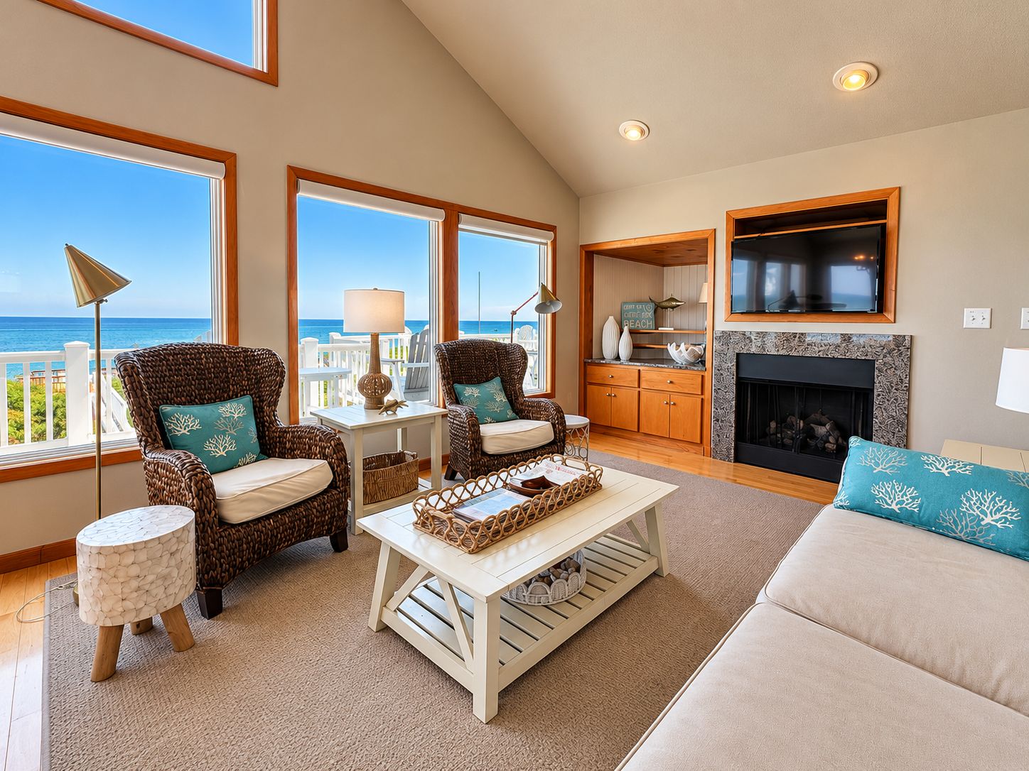 A spacious living room with a fireplace, large windows, and a view of the ocean.