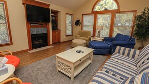 A living room with a fireplace, a television, a sofa, and a coffee table. - Serenity-Too - Oceanside Relaxation, 6 Bed, 4.1 Bath, pool, hot tub, dog friendly! (Southern Shores)