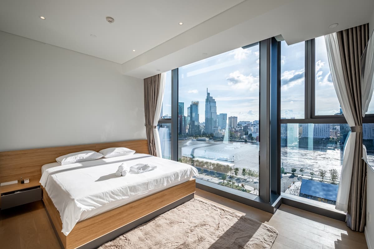 Une chambre moderne avec un grand lit, une vue sur le paysage urbain et une rivière.