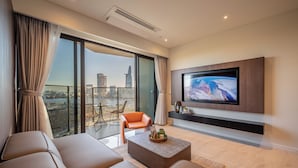 Ein modernes Wohnzimmer mit großem Fernseher, bequemen Sitzmöglichkeiten und Blick auf eine Stadtlandschaft.
