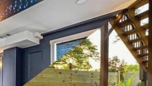 Una vasca idromassaggio in un'area esterna coperta, con un rivestimento in legno e vista su zone verdi.