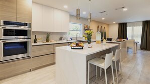 Une cuisine moderne dotée d’appareils électroménagers intégrés, d’un îlot central avec des sièges et d’un coin repas offrant une vue agréable.