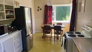 A compact kitchen with a refrigerator, microwave, stove, and a dining table with chairs. - Our Bach. Fish, ski or relax in an amazing alpine setting! (Lake Coleridge)