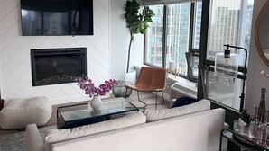 Ein modernes Wohnzimmer mit einem weißen Sofa, einem Glastisch und einem großen Fenster mit Blick auf die Stadt.