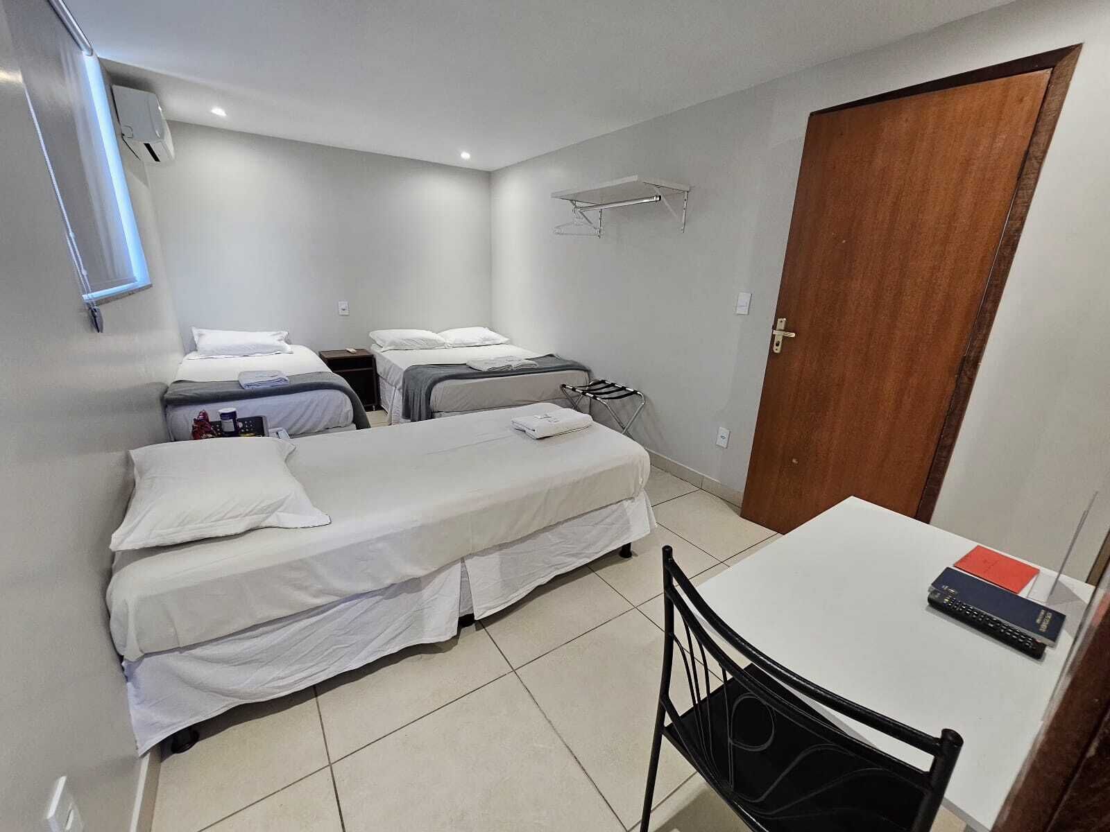 A small, clean room with two beds, a table, and a chair.