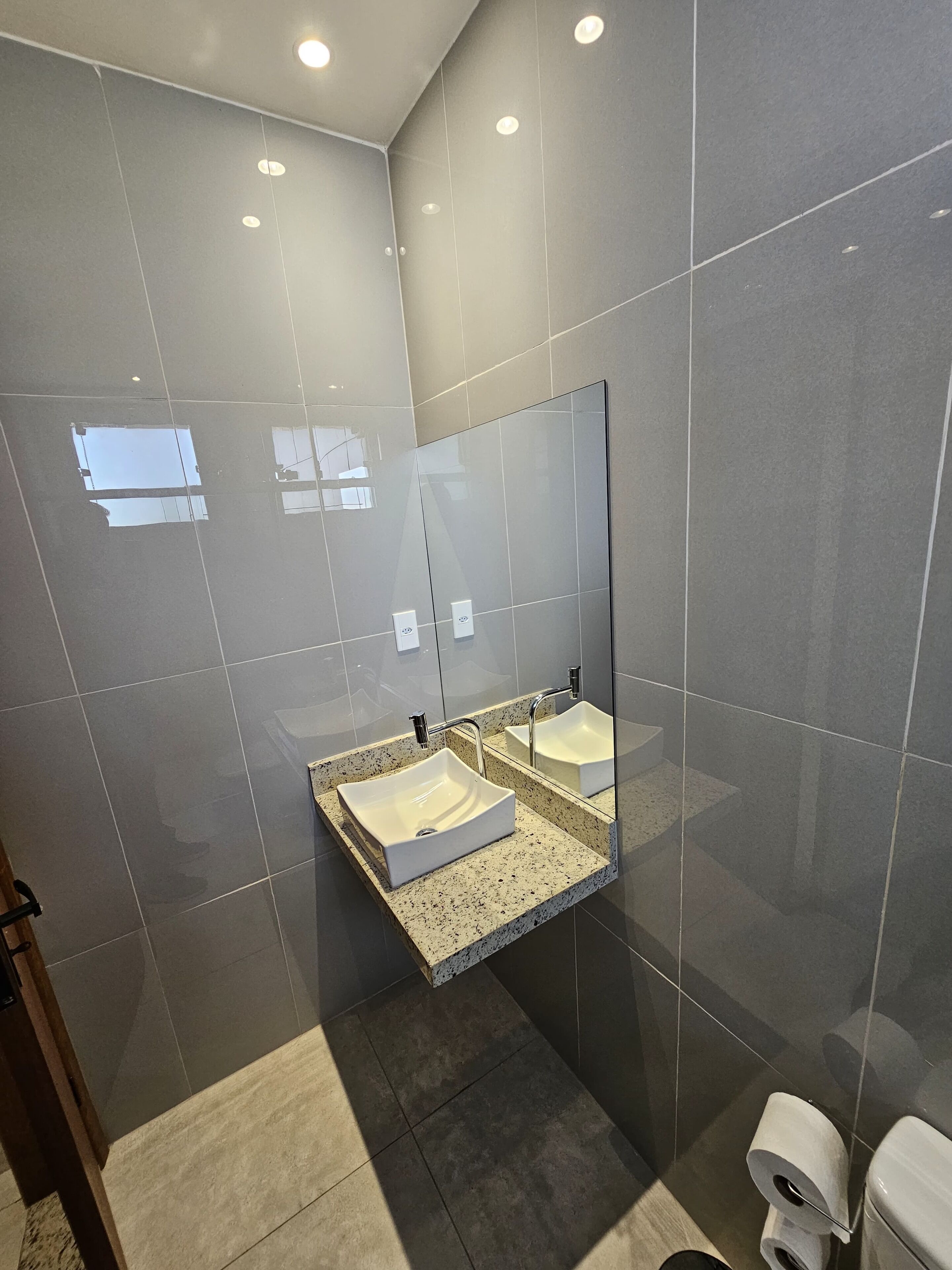 Une salle de bain moderne avec un grand miroir, un lavabo rectangulaire et des toilettes.