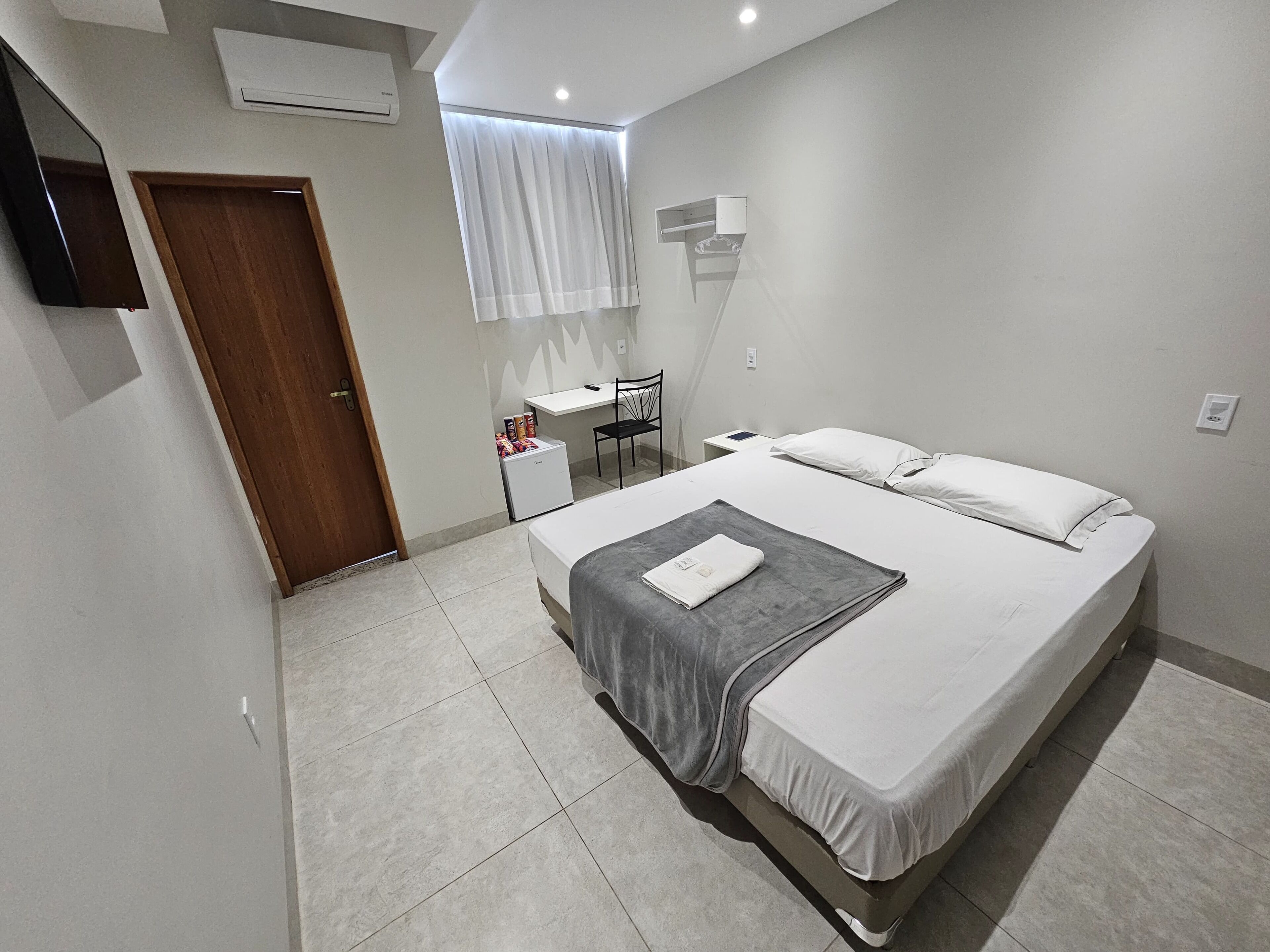 Quarto moderno com uma cama grande, uma escrivaninha e uma cadeira.
