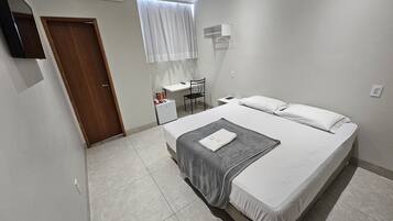 Quarto moderno com uma cama grande, uma escrivaninha e uma cadeira.