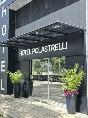Ein moderner Hotel Eingang mit Glasfassade, großen Kübelpflanzen und einem gut sichtbaren Schild 'HOTEL POLASTRELLI'.