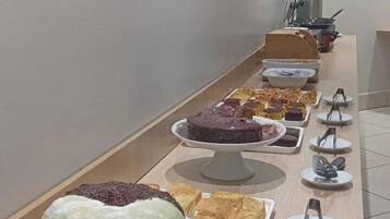 A buffet table with various desserts and a coffee machine in the background.