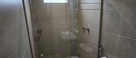 Un baño moderno con ducha envuelta en vidrio, inodoro y bidé.