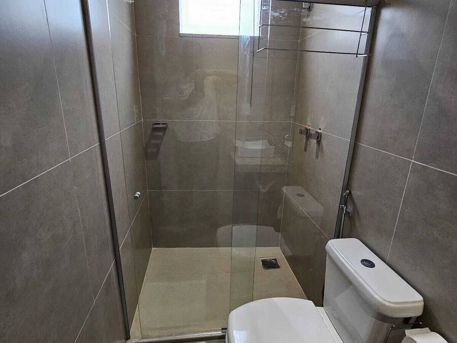 A modern bathroom with a glass-enclosed shower, a toilet, and a sink.