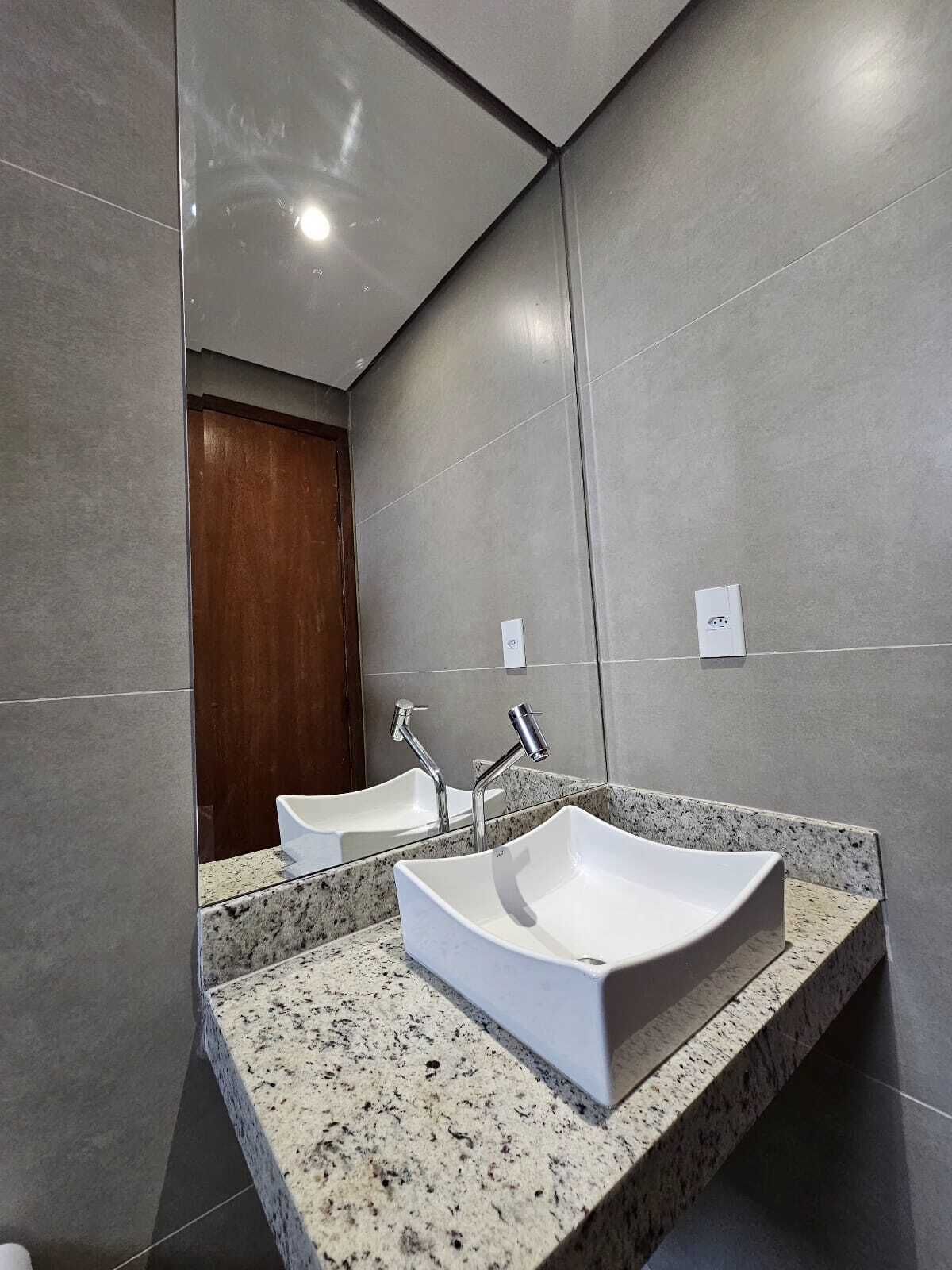 Un baño moderno con dos lavamanos, encimeras de granito y un espejo grande.
