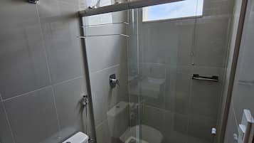 Moderni kylpyhuone, jossa on lasiseinällä varustettu suihku, wc ja pesuallas.