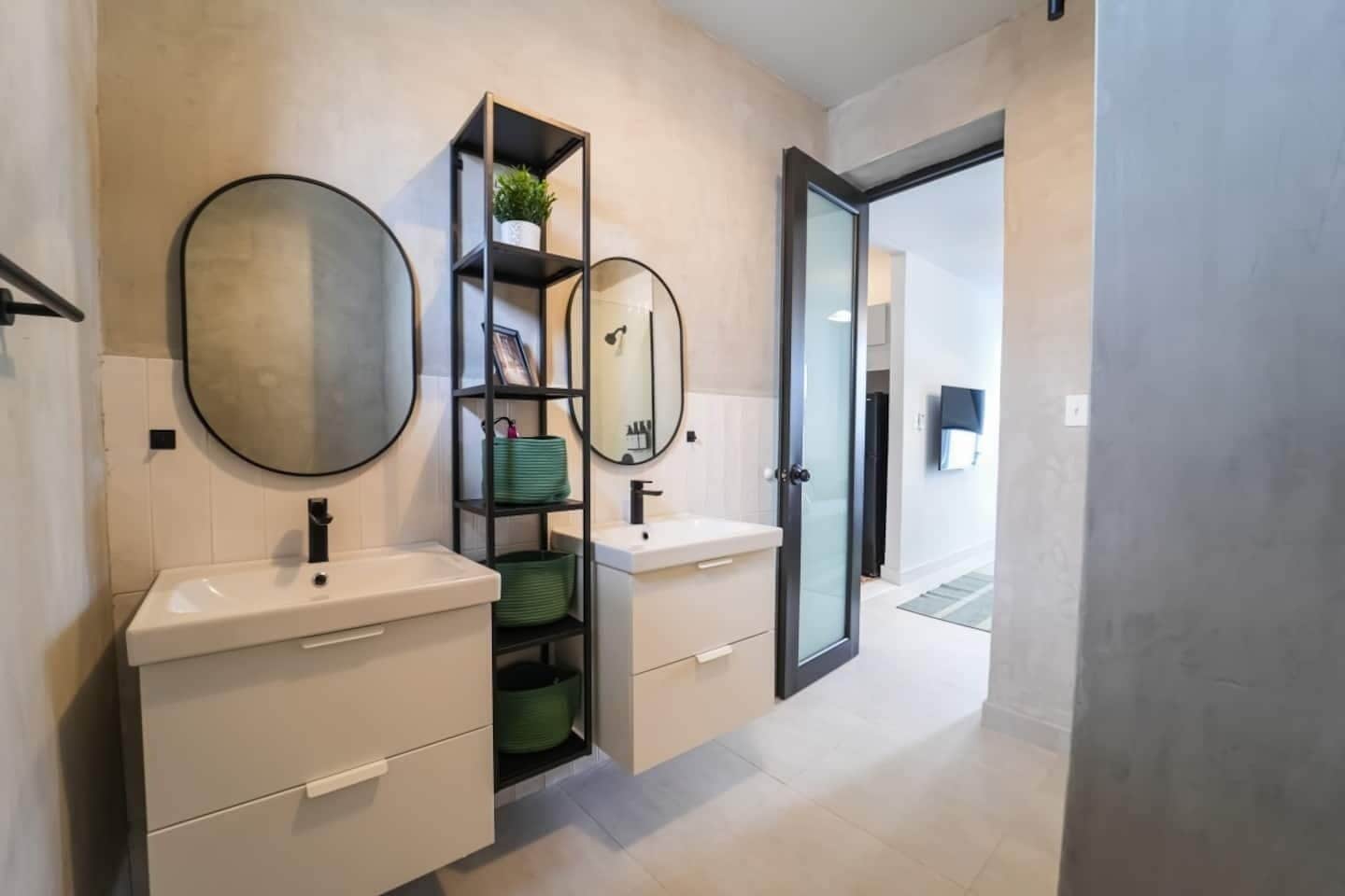 A modern bathroom with two sinks, a mirror, and a built-in shelf with a plant.