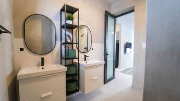 A modern bathroom with two sinks, a mirror, and a built-in shelf with a plant.